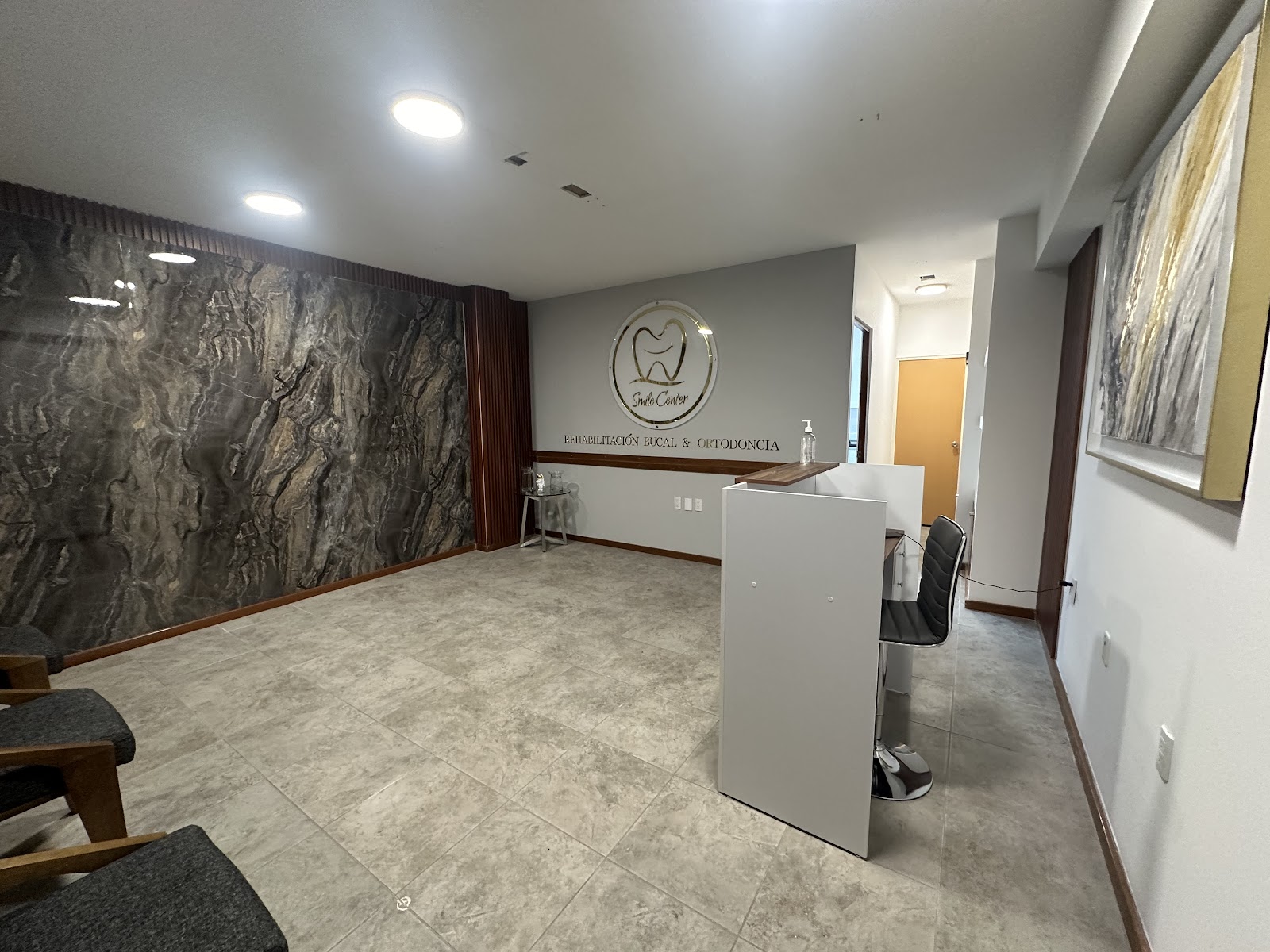 Recepción Smile Center Juriquilla — mármol, dorado y madera oscura